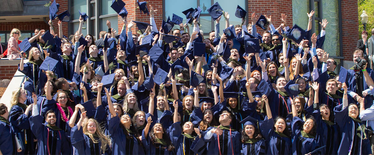 UConn School of Pharmacy students throw their caps in the air following graduation