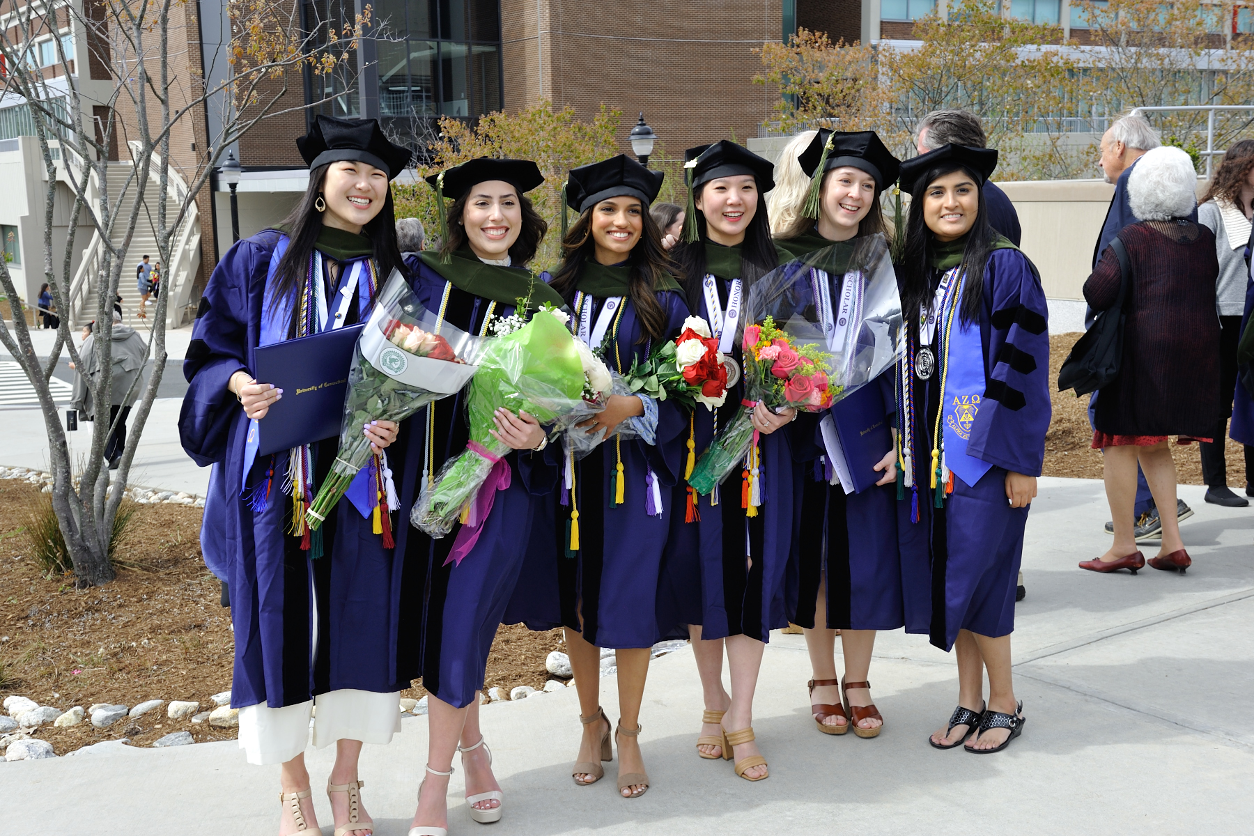 Group of women in graduation caps holding flowers