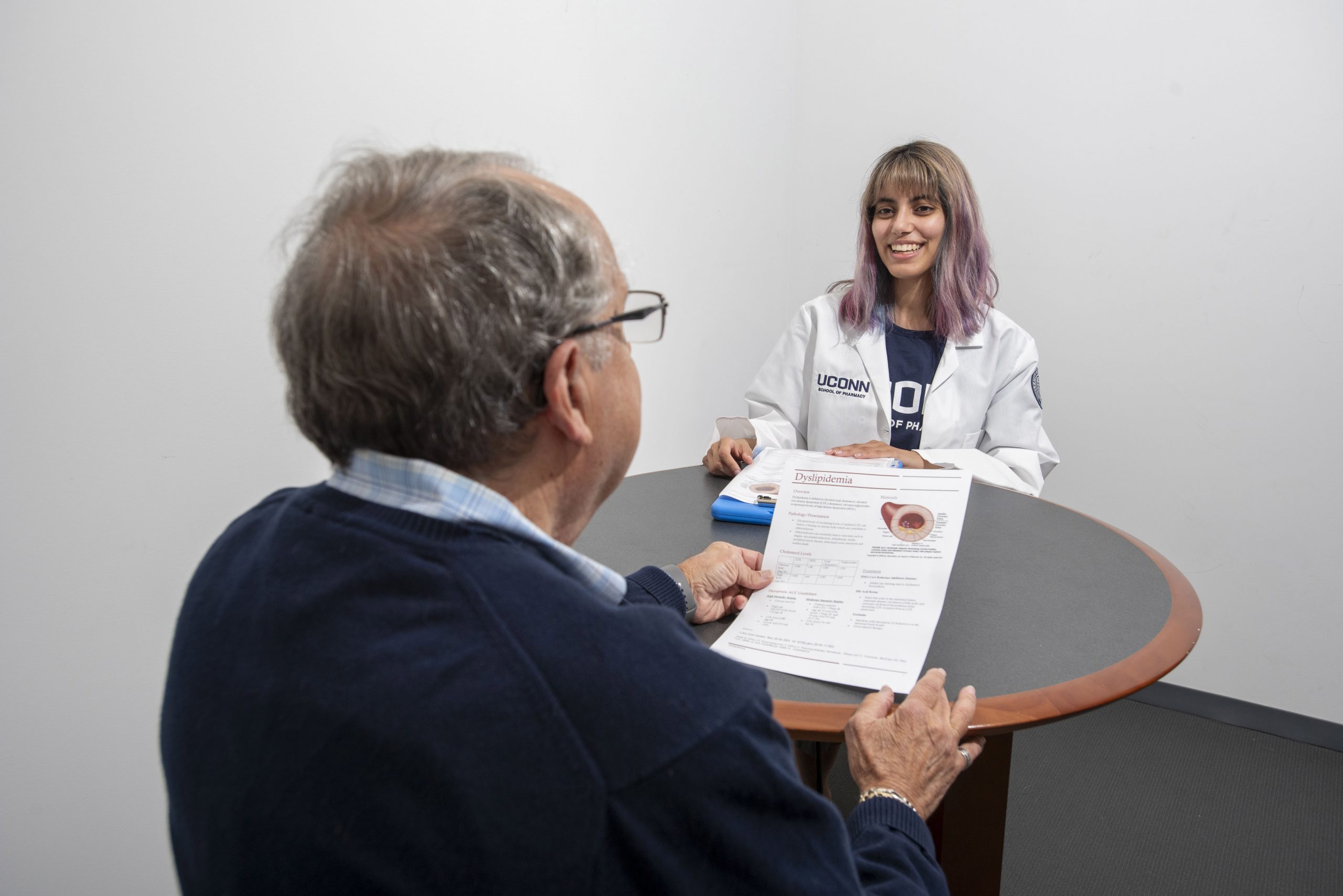 student consulting with older patient reading a form